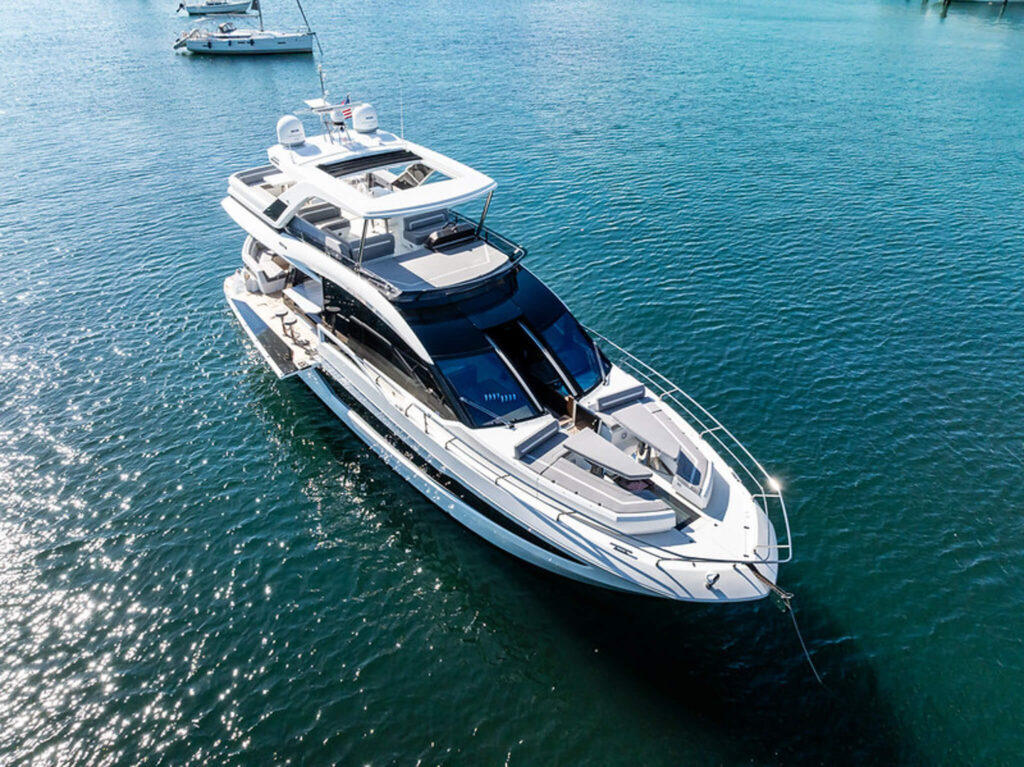 Miami Rent A Yacht A large white luxury yacht is anchored in calm blue water with another boat in the background. Miami Yacht Rental