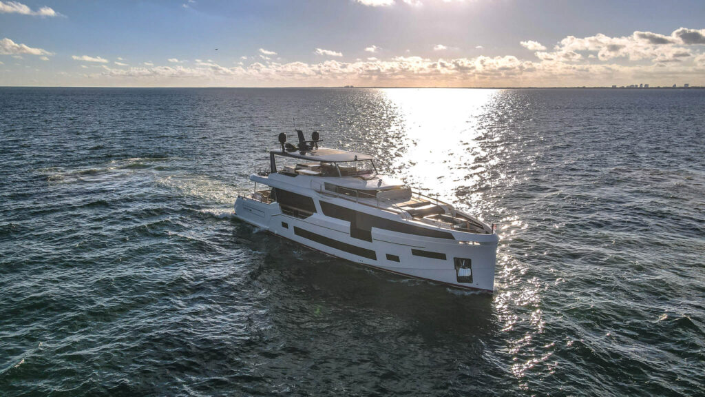 Miami Rent A Yacht A modern white yacht sails on open water under a partly cloudy sky with the sun reflecting on the ocean surface. Miami Yacht Rental